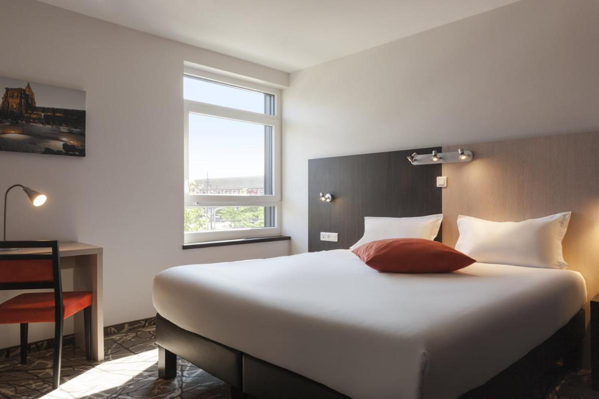 une chambre avec un grand lit blanc et une fenêtre dans l'établissement The Originals Boutique, Hôtel d'Alsace, Strasbourg Sud, à Illkirch-Graffenstaden