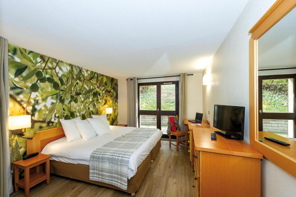 une chambre avec un lit, un bureau et une télévision dans l'établissement Club Vacances Bleues Domaine de Château Laval, à Gréoux-les-Bains