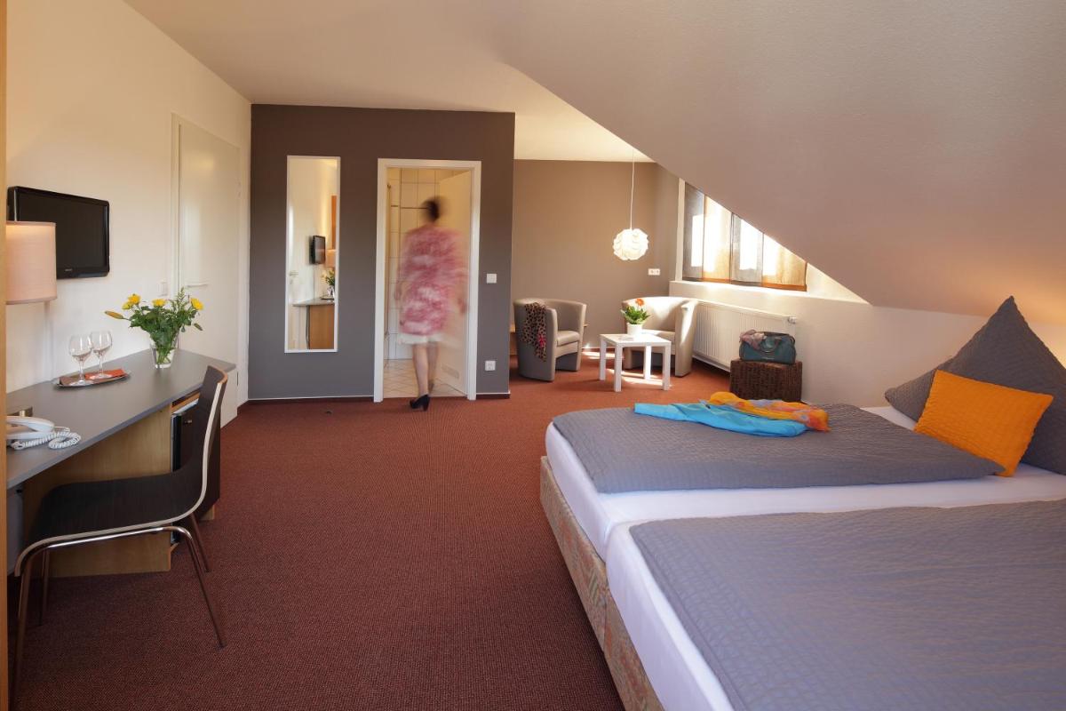 ein Schlafzimmer mit einem Bett und eine Frau, die in ein Zimmer geht in der Unterkunft Hotel Astra Rastatt in Rastatt ein Schlafzimmer mit einem Bett und eine Frau, die in ein Zimmer geht in der Unterkunft Hotel Astra Rastatt in Rastatt