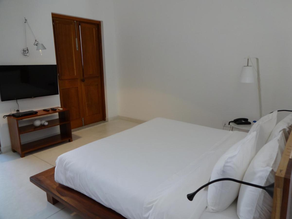 a bedroom with a white bed and a television at La Villa in Puducherry