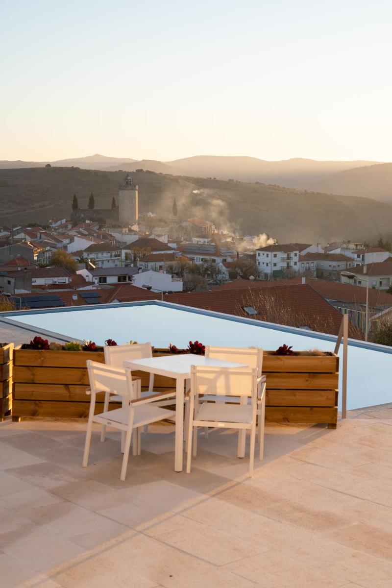 uma mesa branca e cadeiras sentadas num telhado em Hotel Freixo Douro Superior em Freixo de Espada à Cinta
