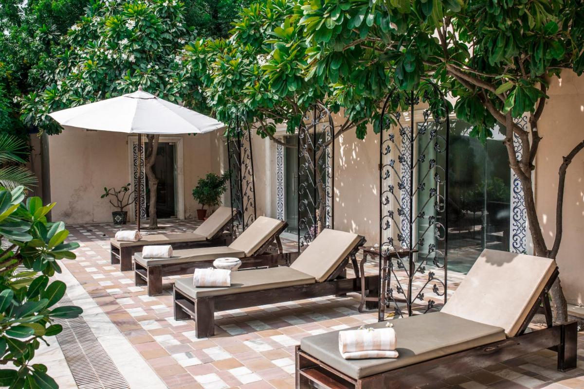 four lounge chairs and an umbrella on a patio at Royal Heritage Haveli - By Leisure Hotels in Jaipur