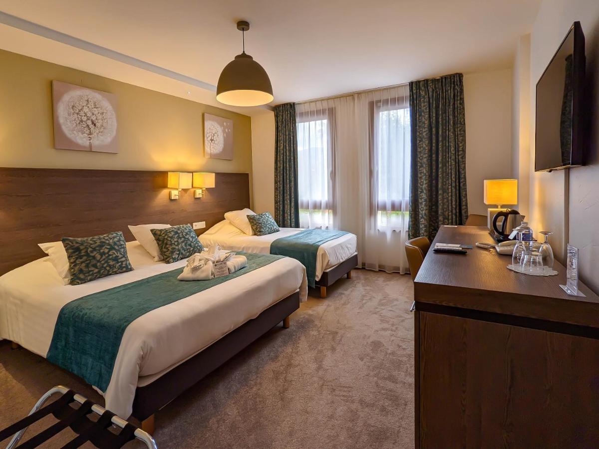 une chambre d'hôtel avec deux lits et un bureau dans l'établissement Hotel Restaurant & Spa Verte Vallée, à Munster
