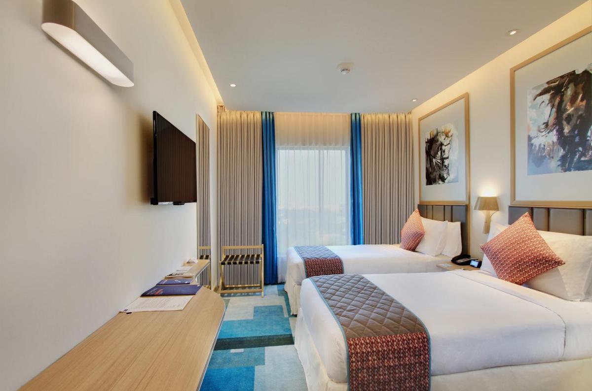 a hotel room with two beds and a television at Holiday Inn Bengaluru Racecourse by IHG in Bengaluru a hotel room with two beds and a television at Holiday Inn Bengaluru Racecourse by IHG in Bengaluru