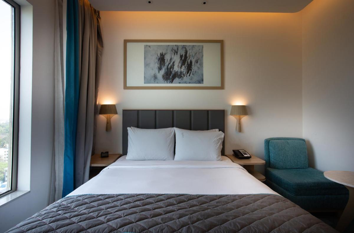 a hotel room with a bed and a blue chair at Holiday Inn Bengaluru Racecourse by IHG in Bengaluru a hotel room with a bed and a blue chair at Holiday Inn Bengaluru Racecourse by IHG in Bengaluru