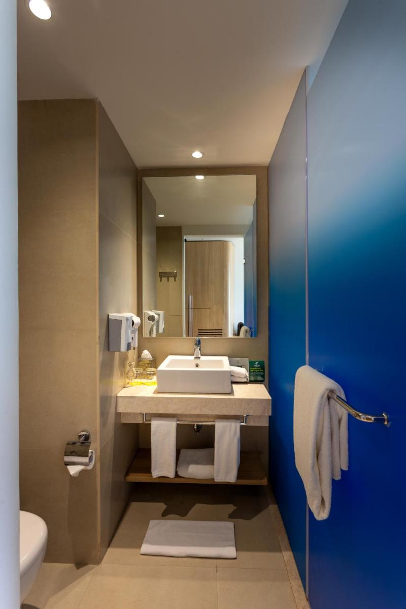 a bathroom with a sink and a mirror at Holiday Inn Bengaluru Racecourse by IHG in Bengaluru a bathroom with a sink and a mirror at Holiday Inn Bengaluru Racecourse by IHG in Bengaluru