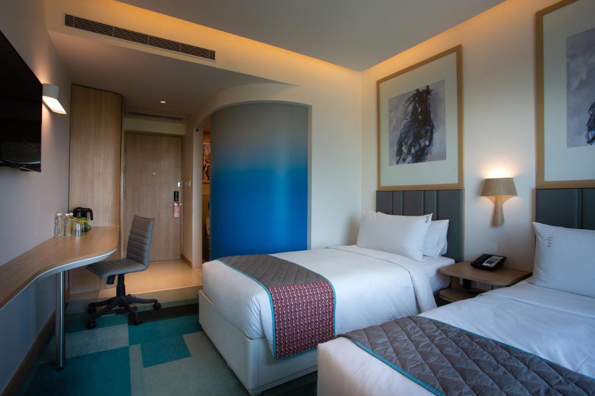 a hotel room with two beds and a desk at Holiday Inn Bengaluru Racecourse by IHG in Bengaluru a hotel room with two beds and a desk at Holiday Inn Bengaluru Racecourse by IHG in Bengaluru