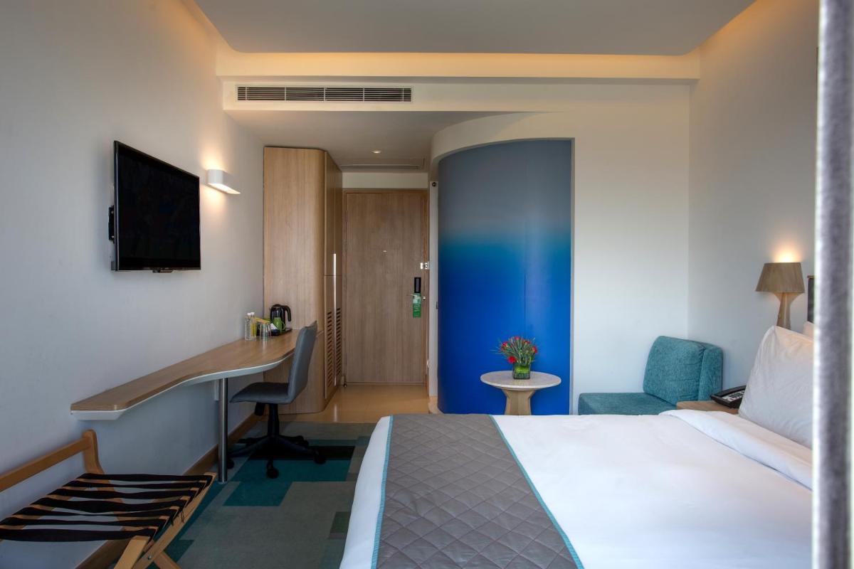 a hotel room with a bed and a desk at Holiday Inn Bengaluru Racecourse by IHG in Bengaluru a hotel room with a bed and a desk at Holiday Inn Bengaluru Racecourse by IHG in Bengaluru