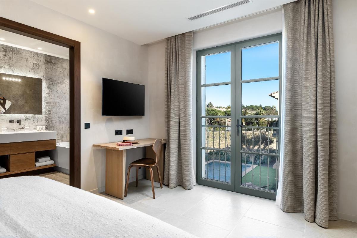 une chambre d'hôtel avec un lit, un bureau et une fenêtre dans l'établissement Villa Cosy, hotel & spa, à Saint-Tropez