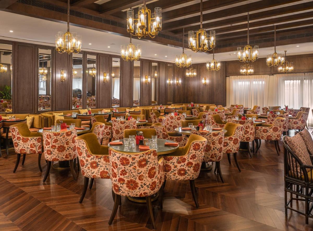 a dining room with tables and chairs and chandeliers at President - IHCL SeleQtions in Mumbai