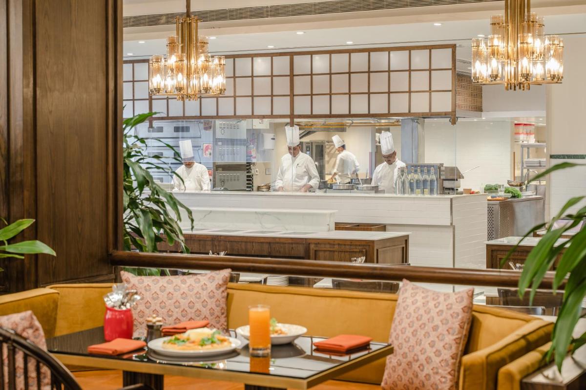 a restaurant with a table and chefs in the kitchen at President - IHCL SeleQtions in Mumbai
