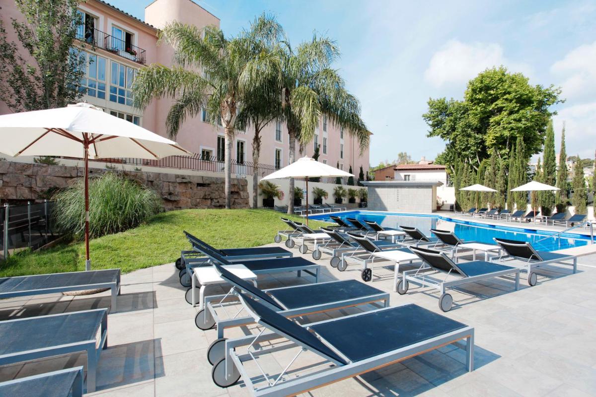 Un grupo de tumbonas y sombrillas junto a una piscina. en Isla Mallorca & Spa, en Palma de Mallorca