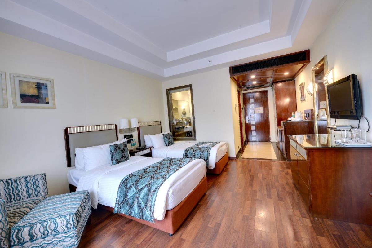 a hotel room with two beds and a flat screen tv at Fortune Select JP Cosmos, Bengaluru - Member ITC Hotels' Group in Bengaluru