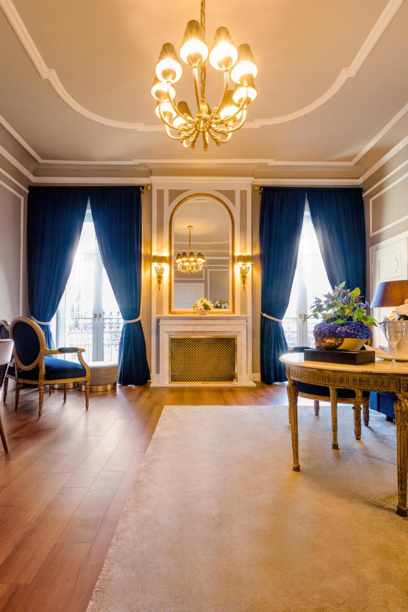ein Wohnzimmer mit blauen Vorhängen und einem Kronleuchter in der Unterkunft Excelsior Hotel Ernst am Dom in Köln