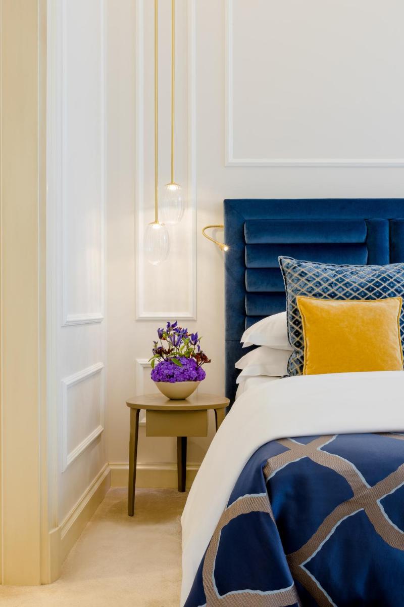 ein Bett mit blauem Kopfteil und ein Tisch mit Blumen in der Unterkunft Excelsior Hotel Ernst am Dom in Köln