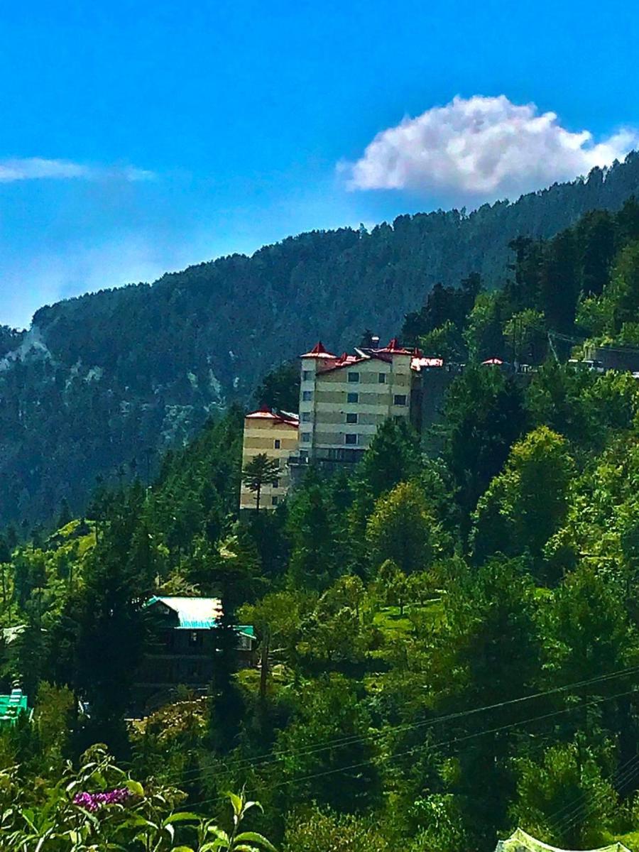 a building on top of a hill with trees at Radisson Kufri in Shimla