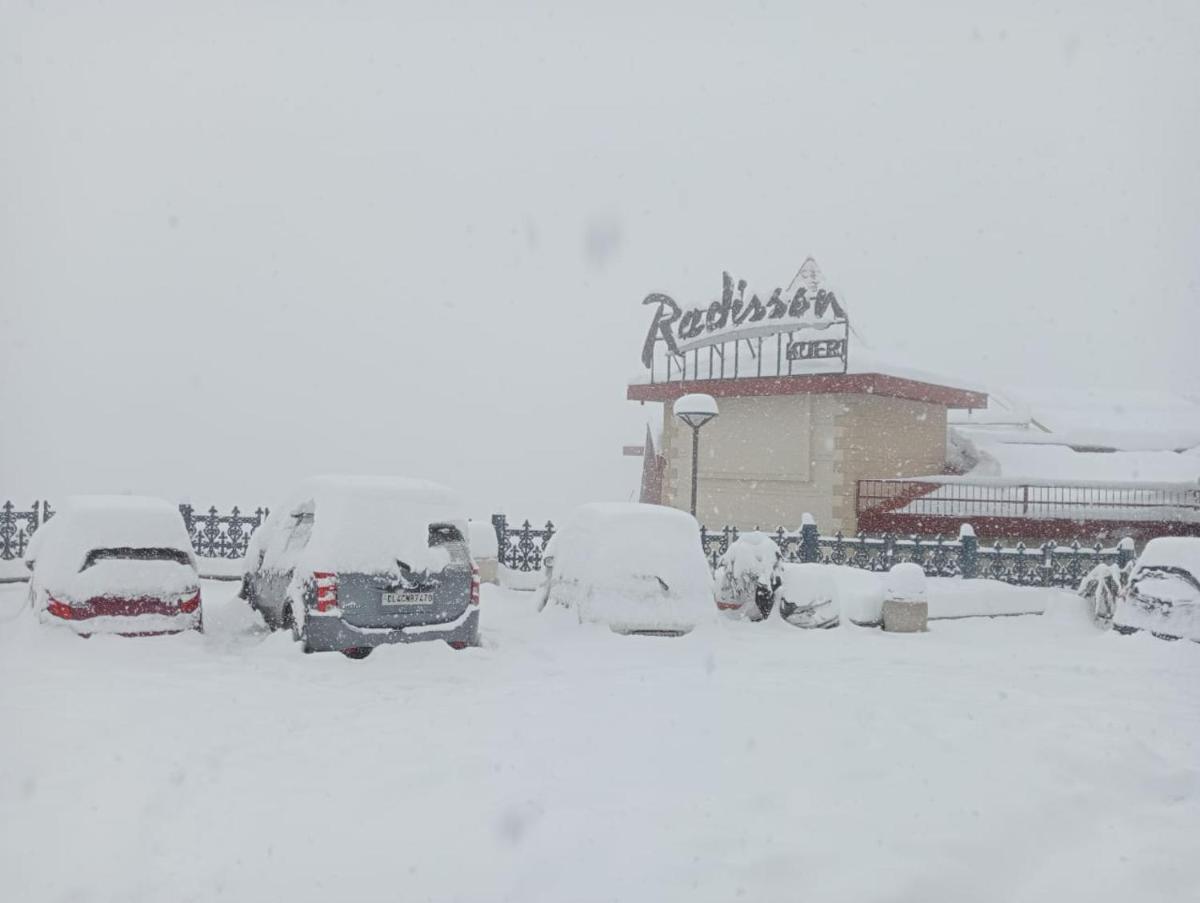 a parking lot covered in snow in front of a restaurant at Radisson Kufri in Shimla