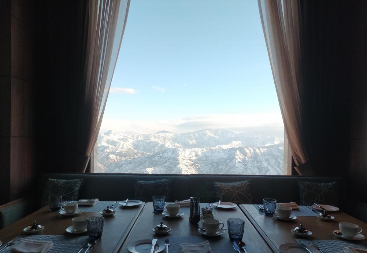 a table with a view of the mountains from a window at Radisson Kufri in Shimla