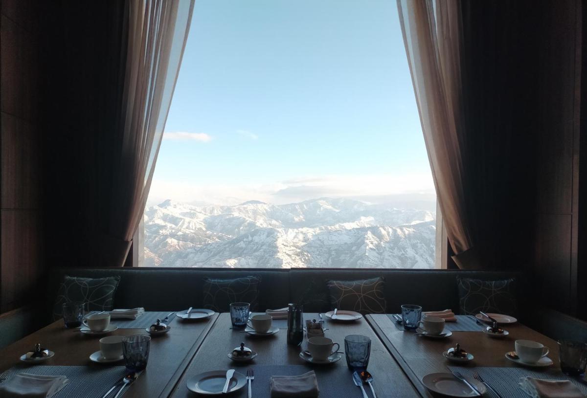 a table with a view of the mountains from a window at Radisson Kufri in Shimla