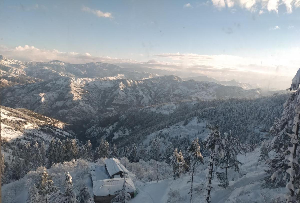 a view of a snow covered mountain range with trees at Radisson Kufri in Shimla