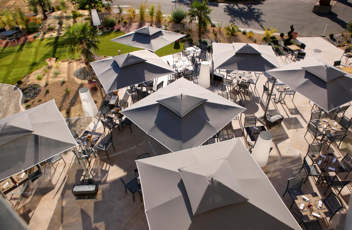 Vue de tête d'un groupe de tables avec parapluies dans l'établissement Hotel Plaza - site du Futuroscope, à Chasseneuil-du-Poitou