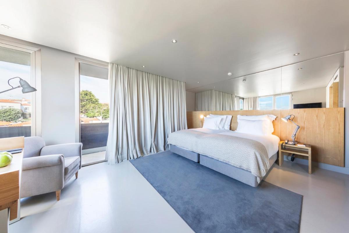 um quarto com uma cama, uma cadeira e uma janela em Villa C Boutique Hotel em Vila do Conde