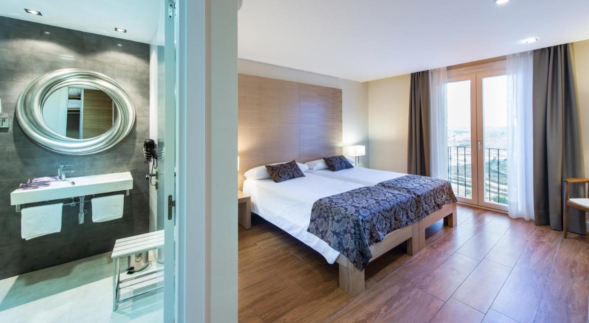 Un dormitorio con una cama, un lavabo y un espejo. en Hotel MedinaSalim, en Medinaceli
