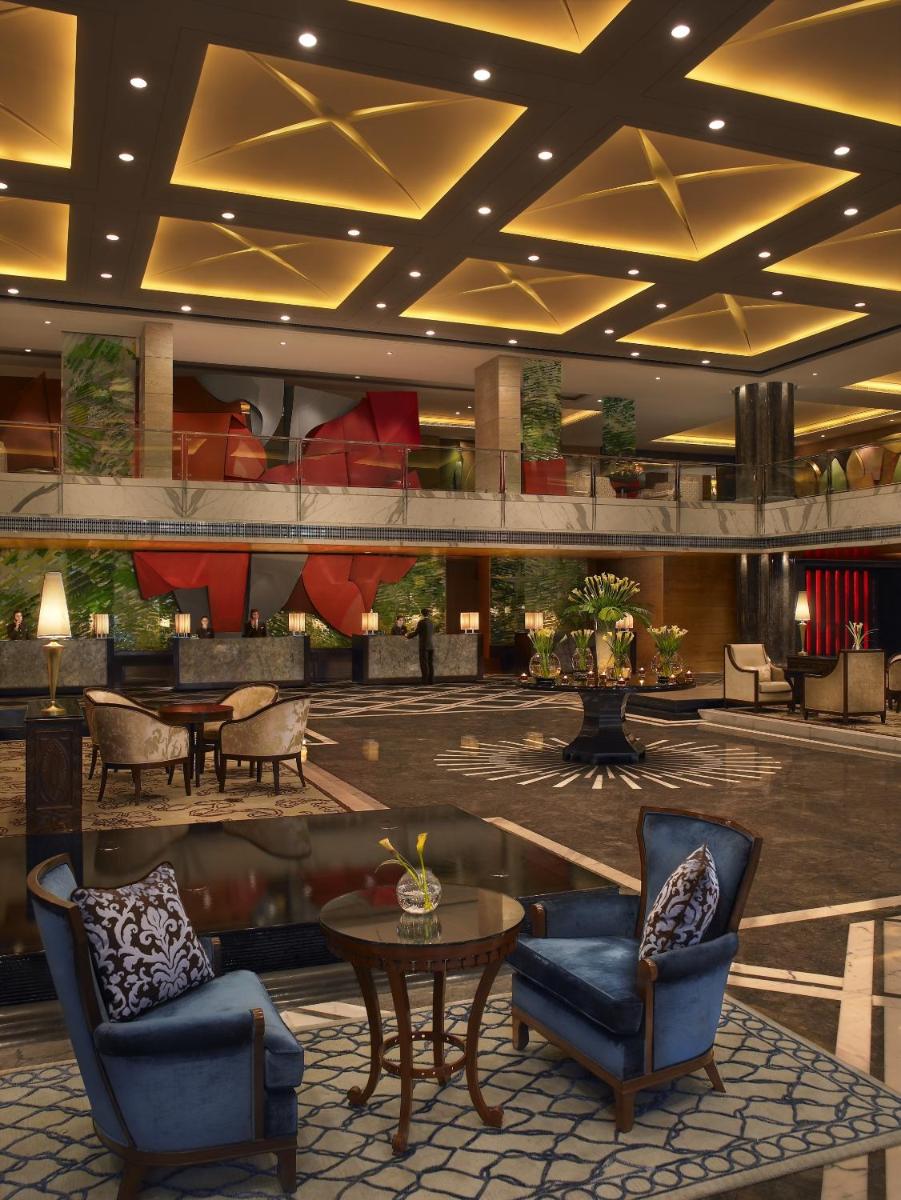 a lobby with chairs and tables in a building at The Leela Ambience Gurugram Hotel & Residences - The Luxury Urban Sanctuary in Gurgaon