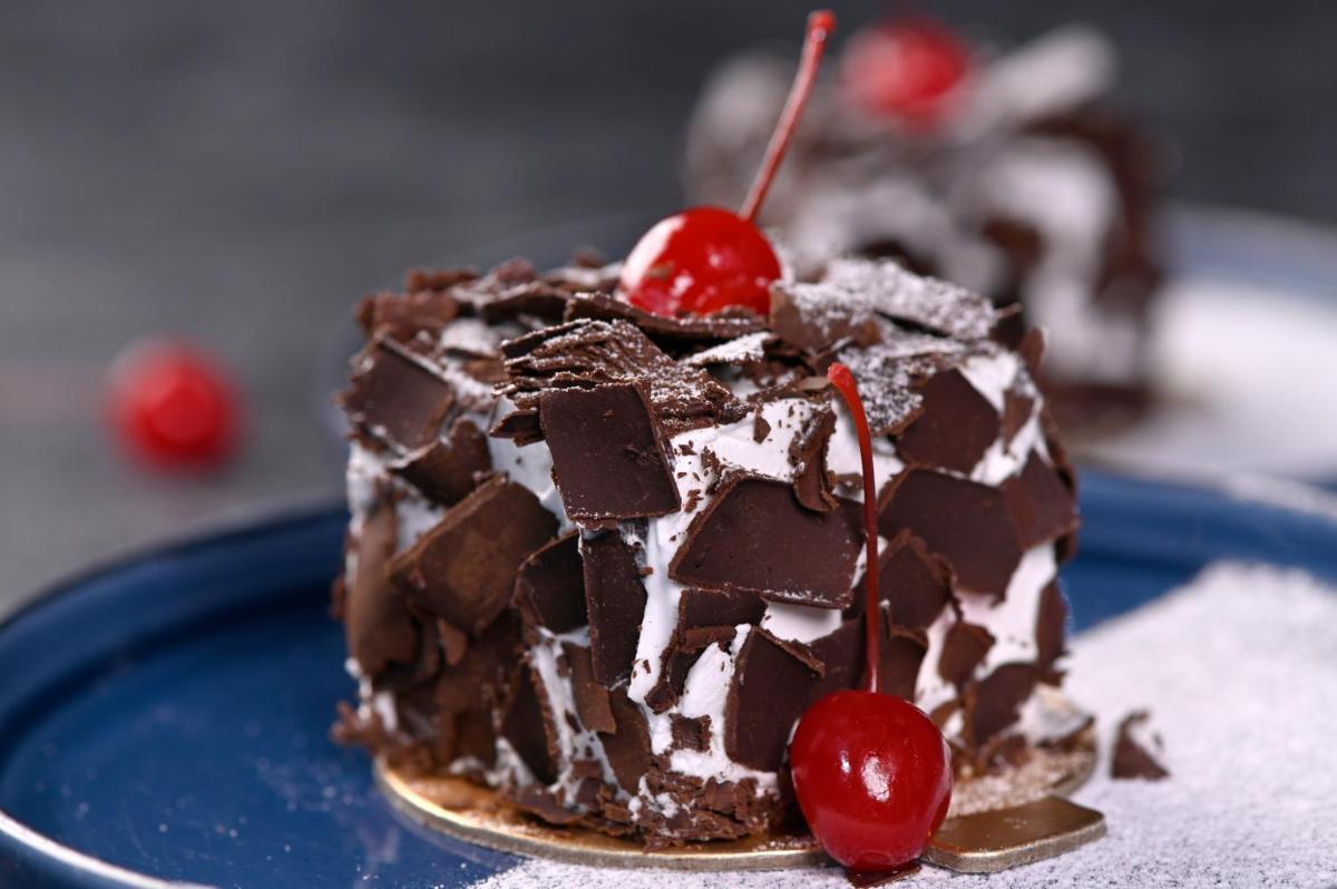 a chocolate cake with a cherry on a blue plate at Novotel Kolkata Hotel and Residences in Kolkata a chocolate cake with a cherry on a blue plate at Novotel Kolkata Hotel and Residences in Kolkata