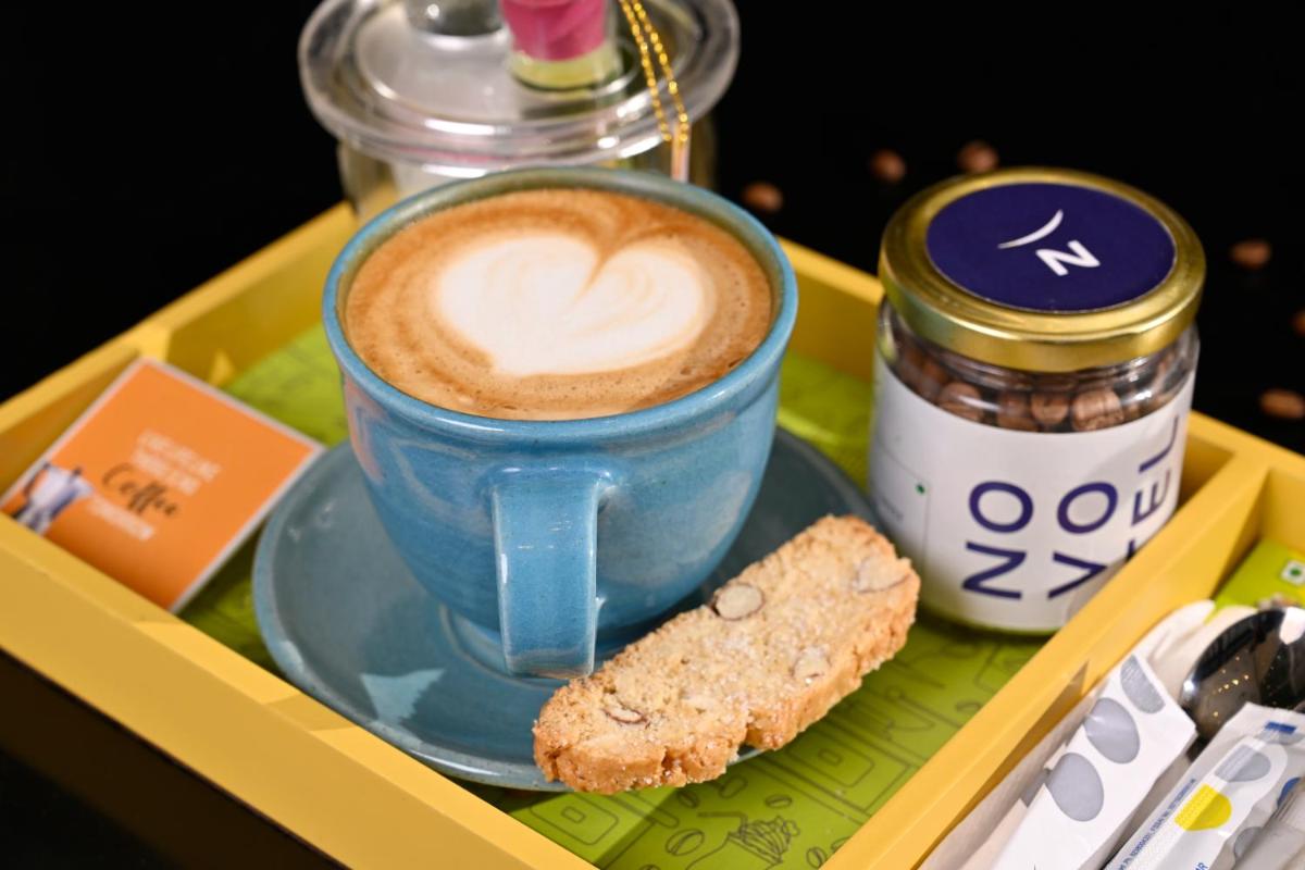 a cup of coffee and a cookie on a tray at Novotel Kolkata Hotel and Residences in Kolkata a cup of coffee and a cookie on a tray at Novotel Kolkata Hotel and Residences in Kolkata