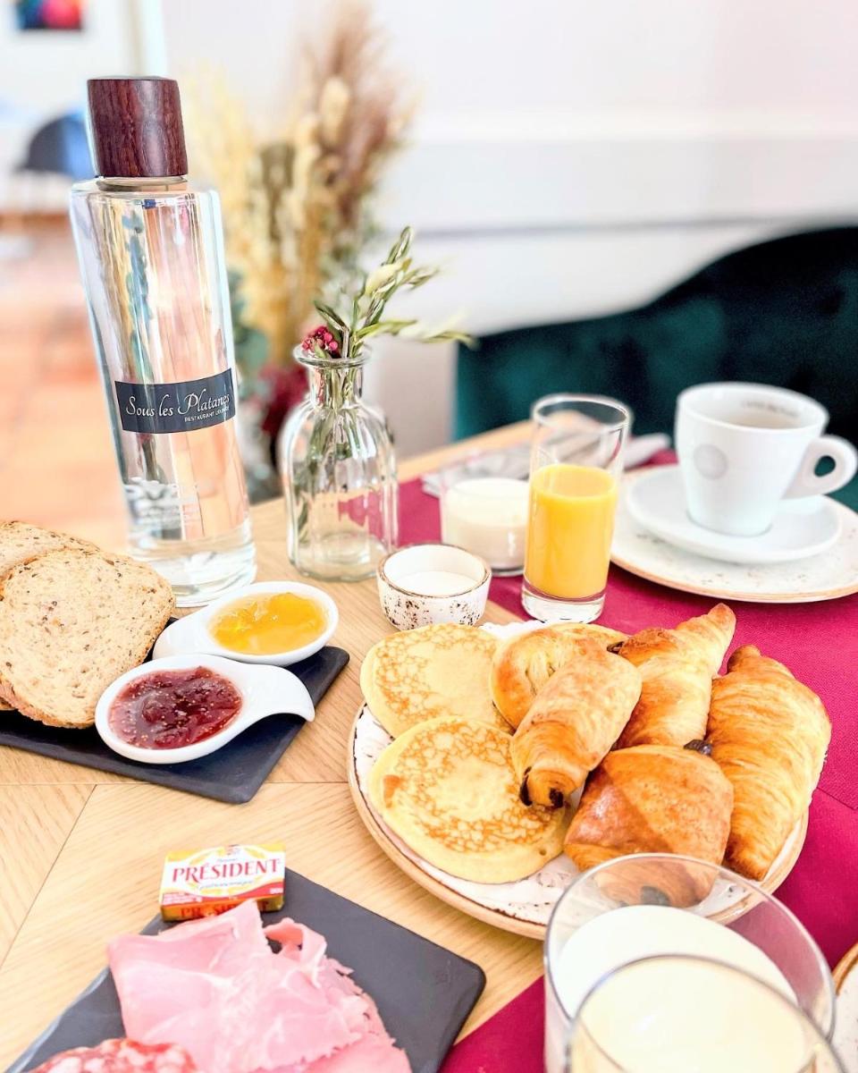 une table recouverte de assiettes de pain et de tasses de jus d'orange dans l'établissement Hôtel Le Mas des Grès & Restaurant Sous les Platanes, à Lagnes