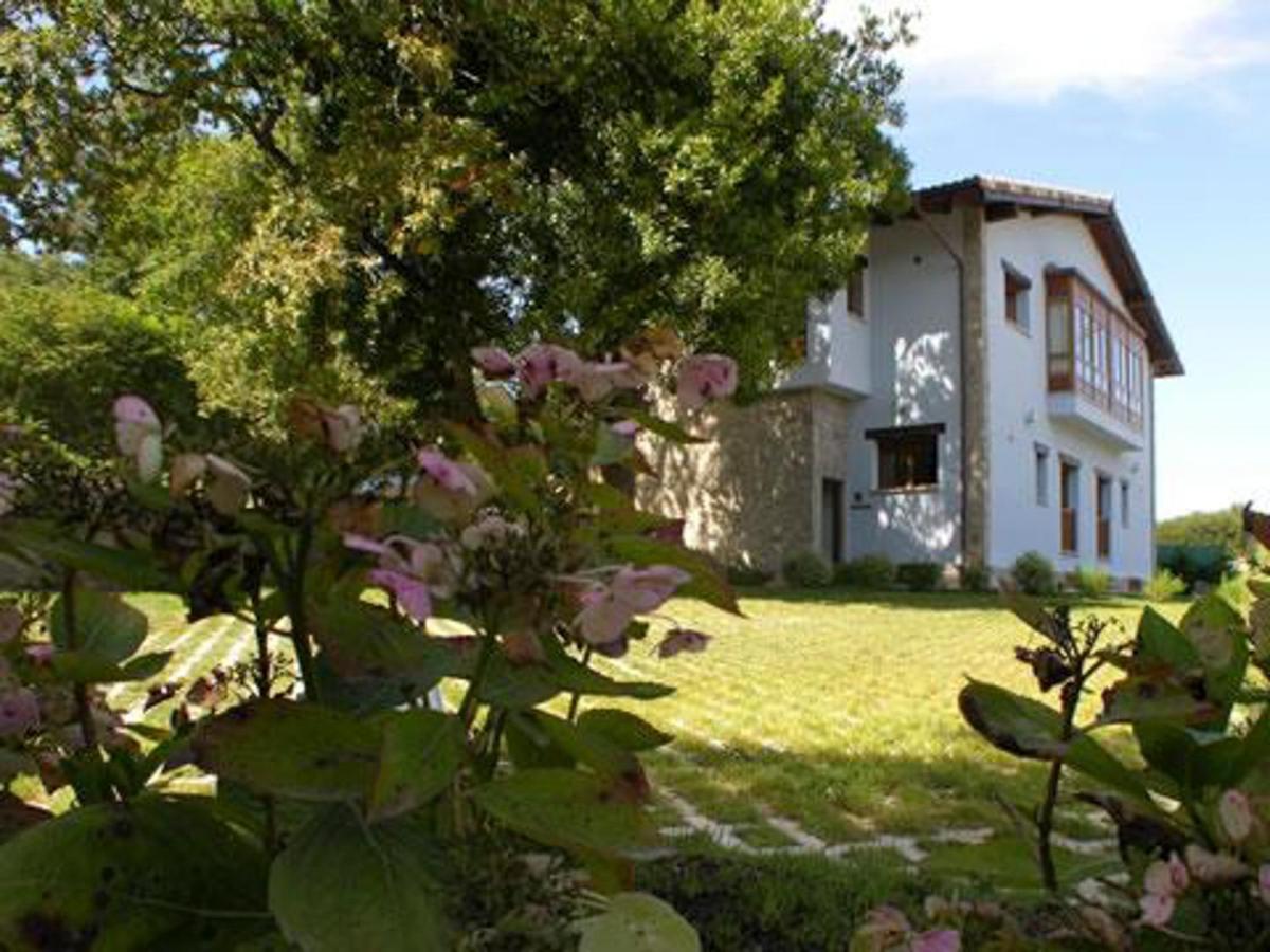 una casa en medio de un patio con flores en LA CASONA Encanto Rural - ApartaHotel SPA Llanes, en Llanes