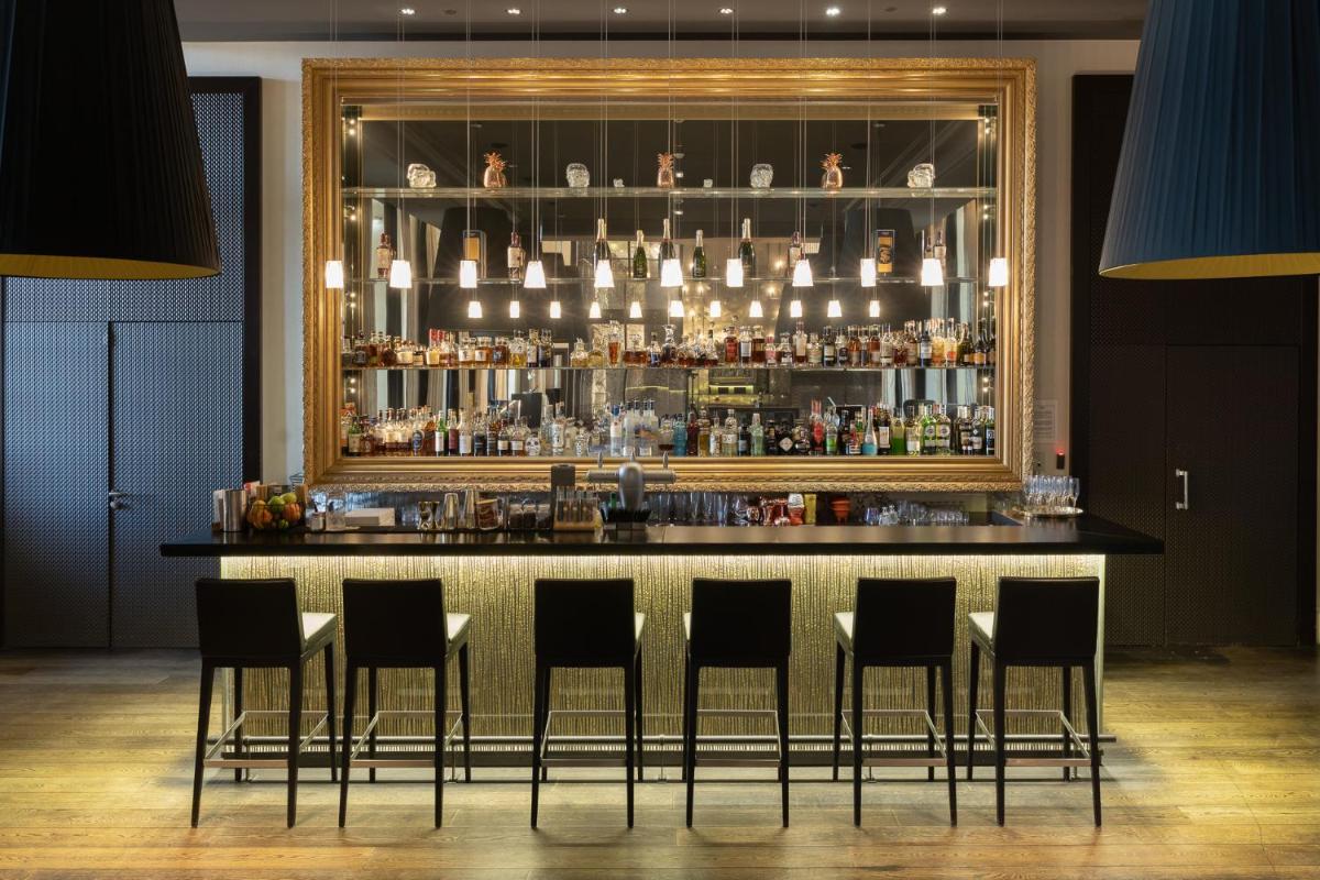 un bar avec des chaises noires et un miroir derrière dans l'établissement InterContinental Marseille - Hotel Dieu by IHG, à Marseille