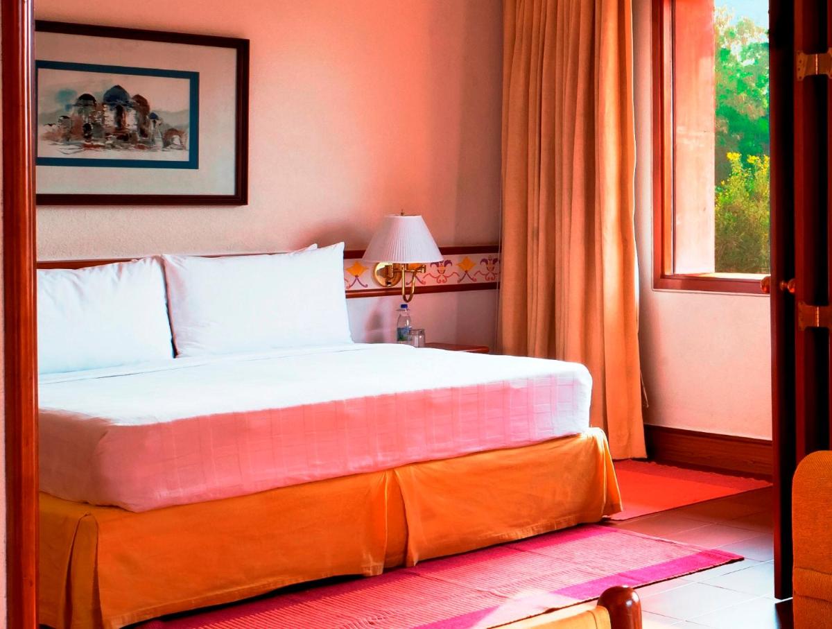 a bedroom with a large bed with an orange wall at Trident Agra in Agra