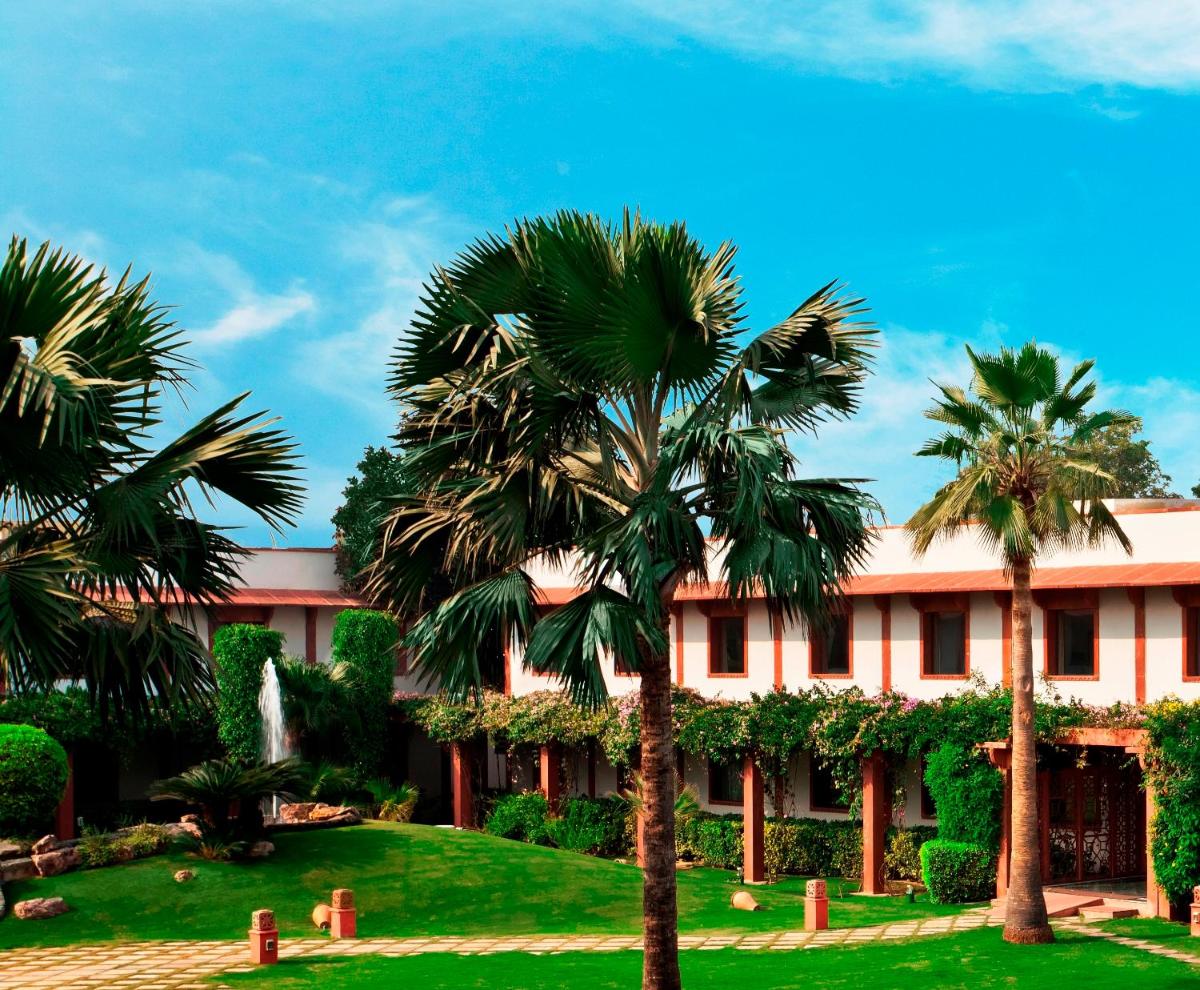 a building with palm trees in front of it at Trident Agra in Agra