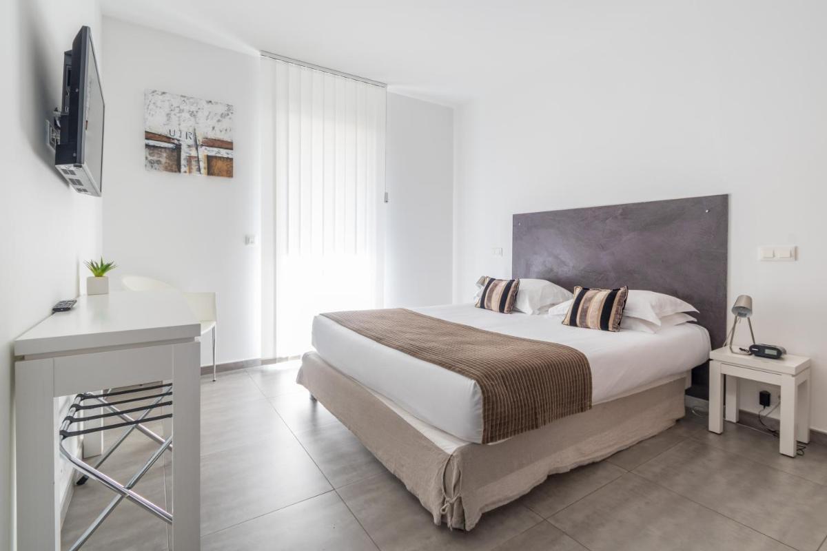 une chambre blanche avec un grand lit et un bureau dans l'établissement Résidence Dary, à LʼÎle-Rousse