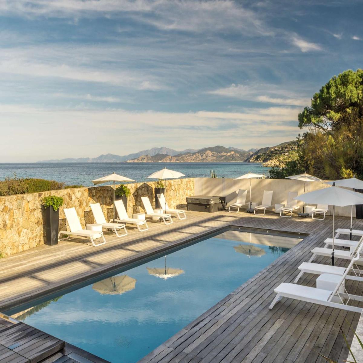une piscine avec chaises longues et parasols dans l'établissement Résidence Dary, à LʼÎle-Rousse