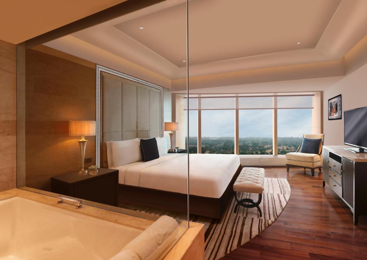 a hotel room with a bed and a bath tub at The Leela Ambience Gurugram Hotel & Residences - The Luxury Urban Sanctuary in Gurgaon