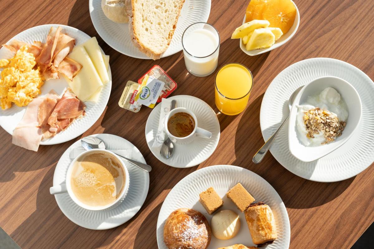 uma mesa de madeira coberta com pratos de comida de café da manhã em Hotel Freixo Douro Superior em Freixo de Espada à Cinta