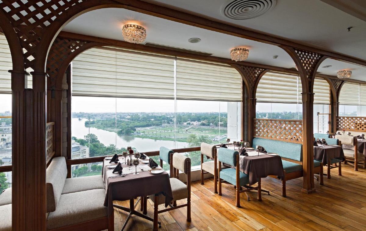 a restaurant with tables and chairs and a large window at Clarks Avadh in Lucknow
