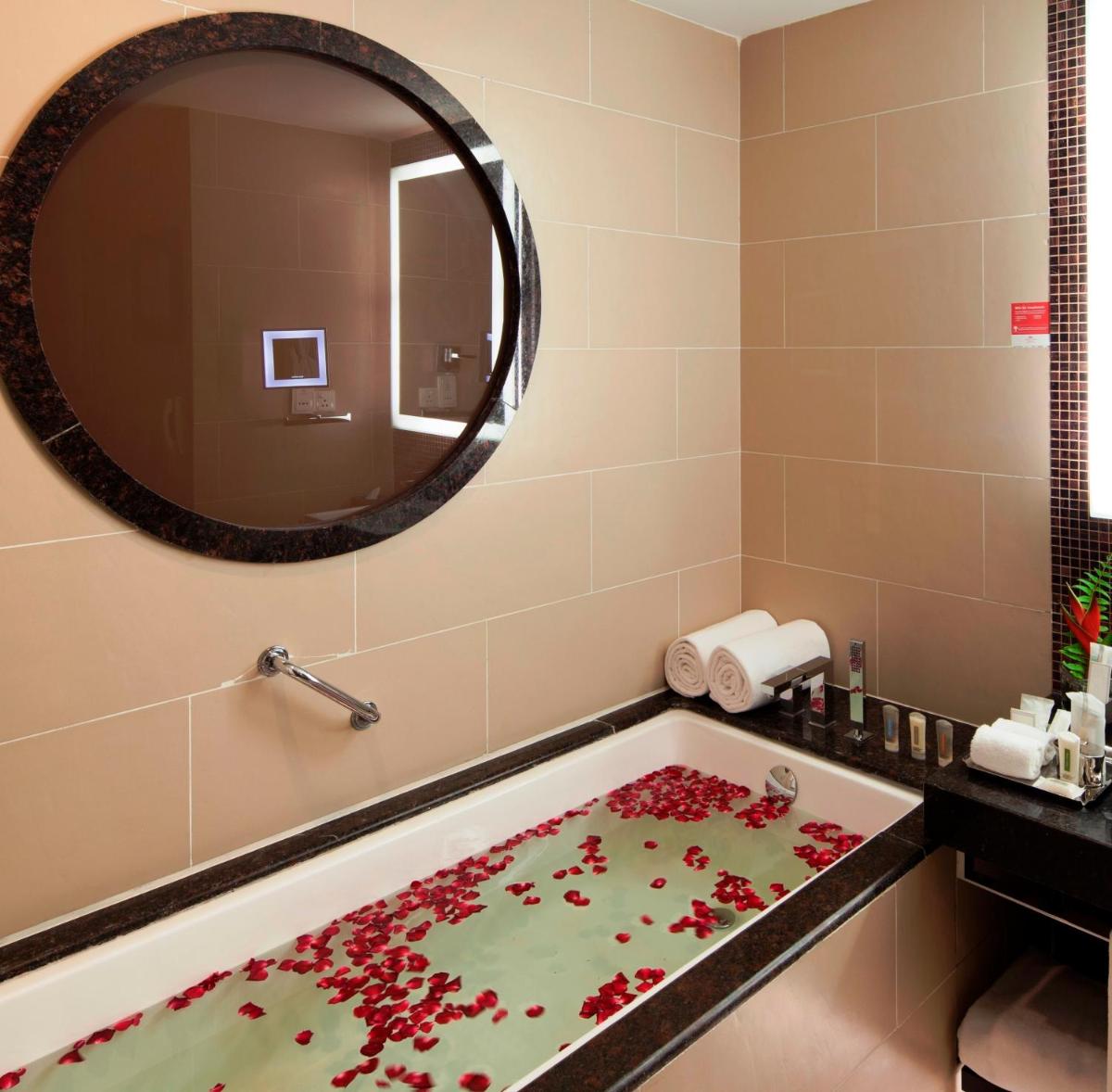 a bathroom with a bath tub with a large mirror at The Oterra in Bengaluru