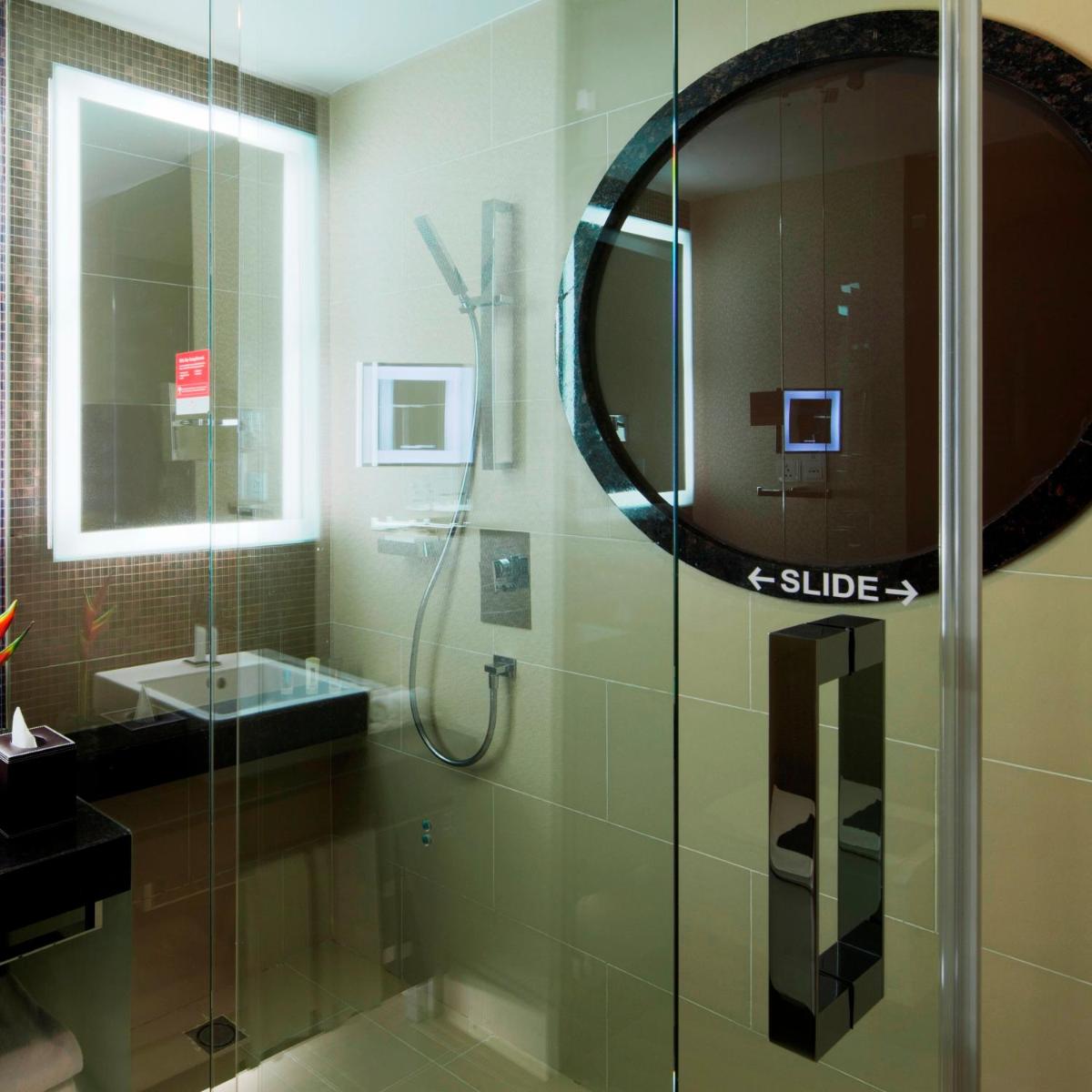 a bathroom with a shower with a mirror and a sink at The Oterra in Bengaluru