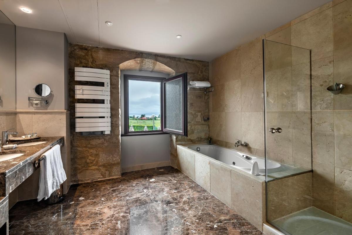Un baño con bañera, lavabo y ventana. en CoolRooms Palacio de Luces, en Luces
