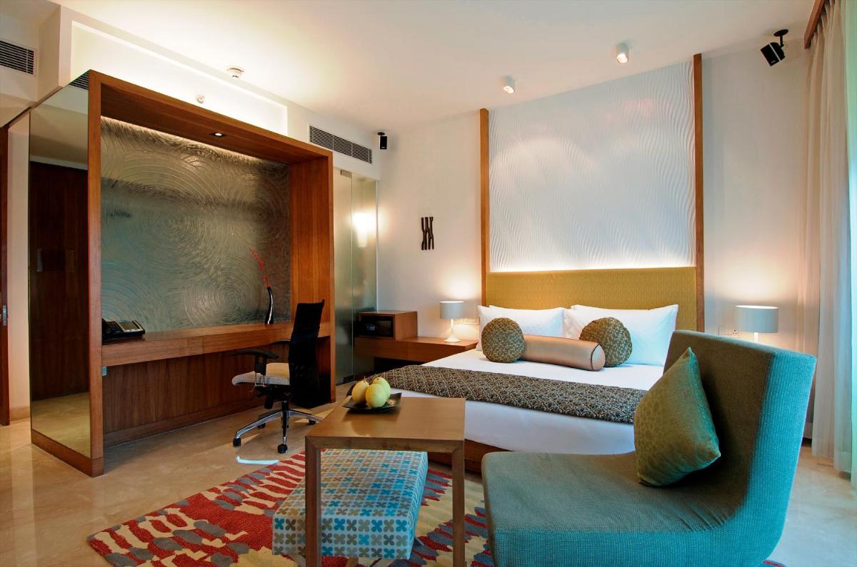 a hotel room with a bed and a desk and chair at Vivanta Bengaluru, Whitefield in Bengaluru