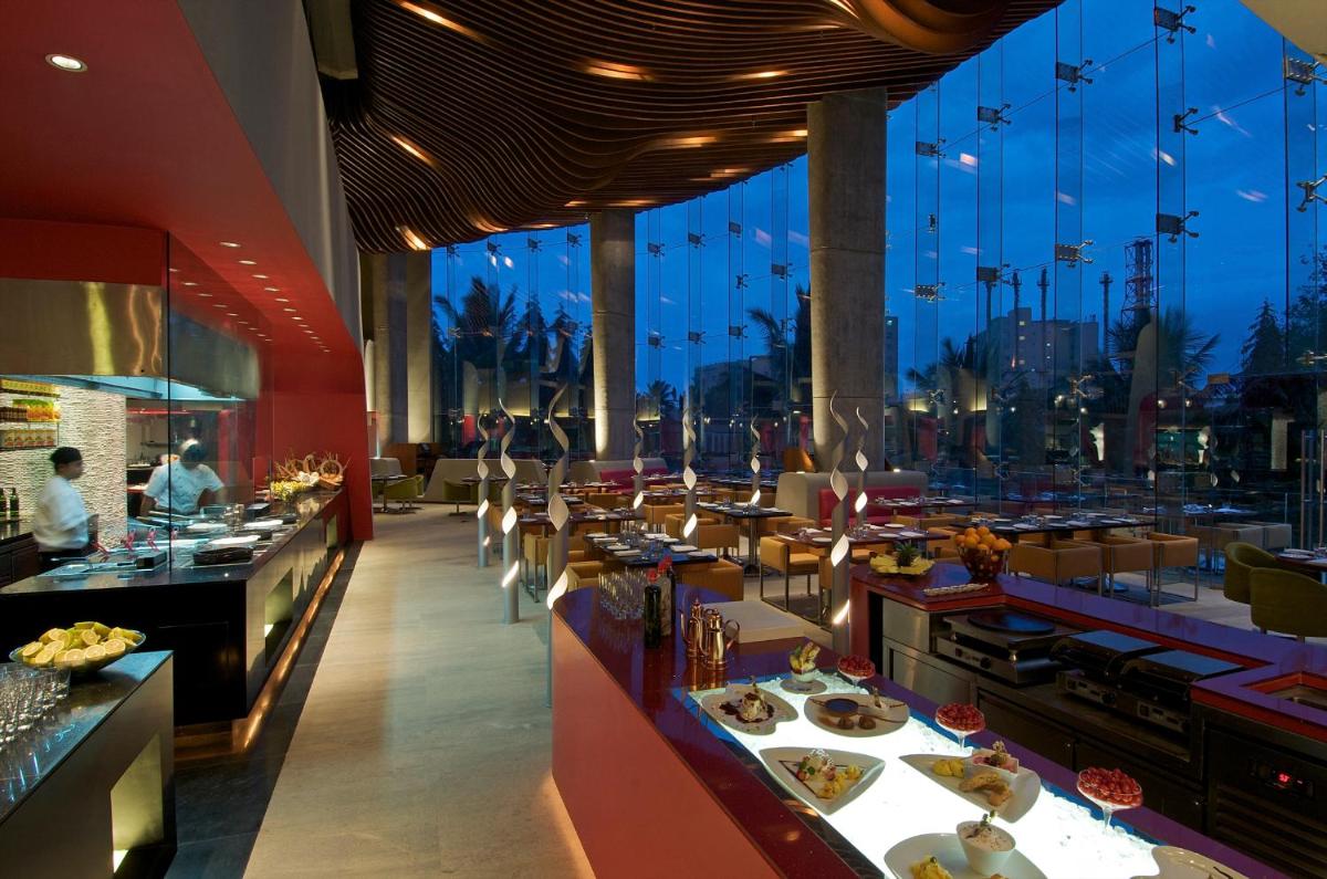a restaurant with a buffet line with a view of the city at Vivanta Bengaluru, Whitefield in Bengaluru