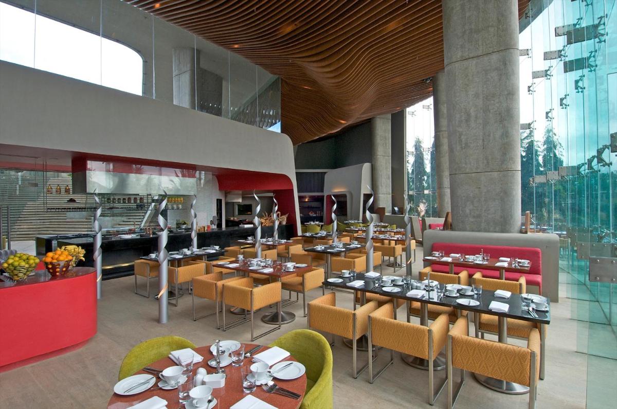 a restaurant with tables and chairs in a building at Vivanta Bengaluru, Whitefield in Bengaluru