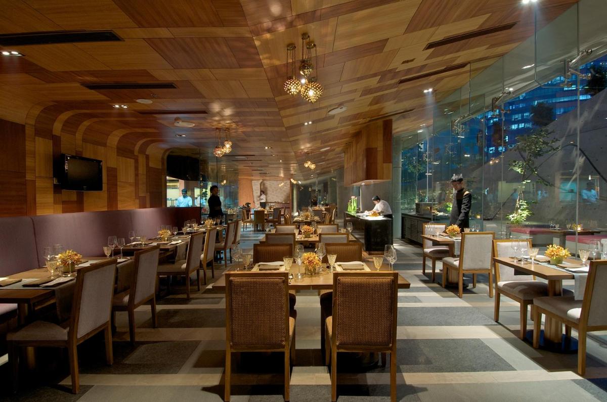 a restaurant with tables and chairs and people in the background at Vivanta Bengaluru, Whitefield in Bengaluru
