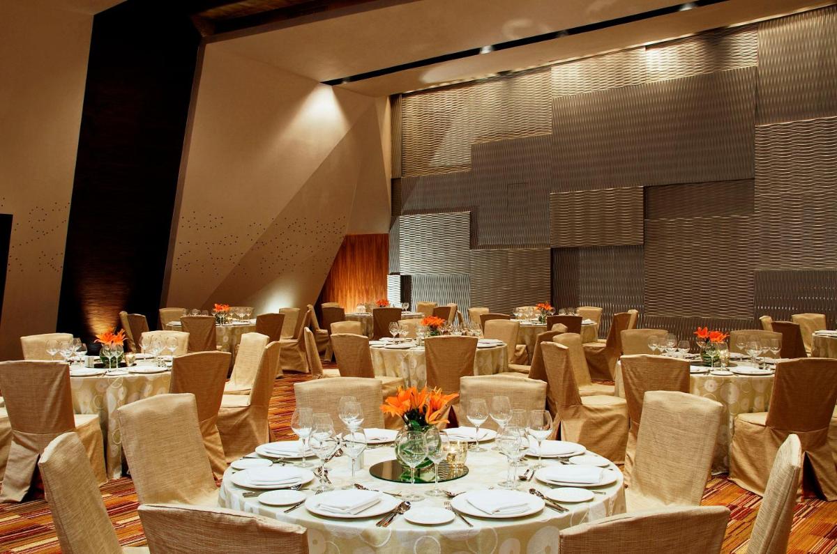 a banquet hall with white tables and chairs at Vivanta Bengaluru, Whitefield in Bengaluru