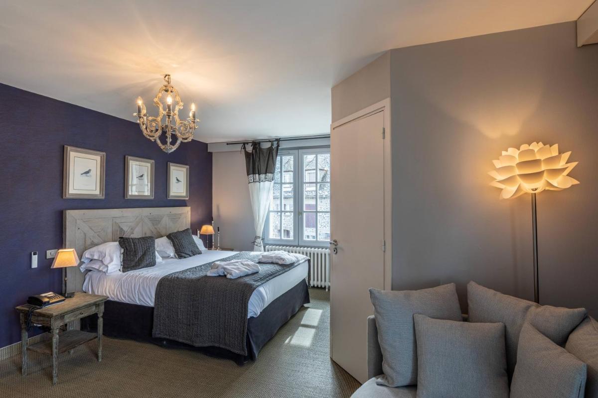 - une chambre avec un lit, un canapé et un lustre dans l'établissement Le Bailliage Hôtel & Spa, à Salers