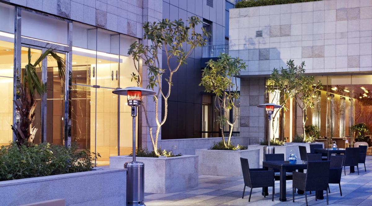a restaurant with tables and chairs in front of a building at Taj City Centre Gurugram in Gurgaon